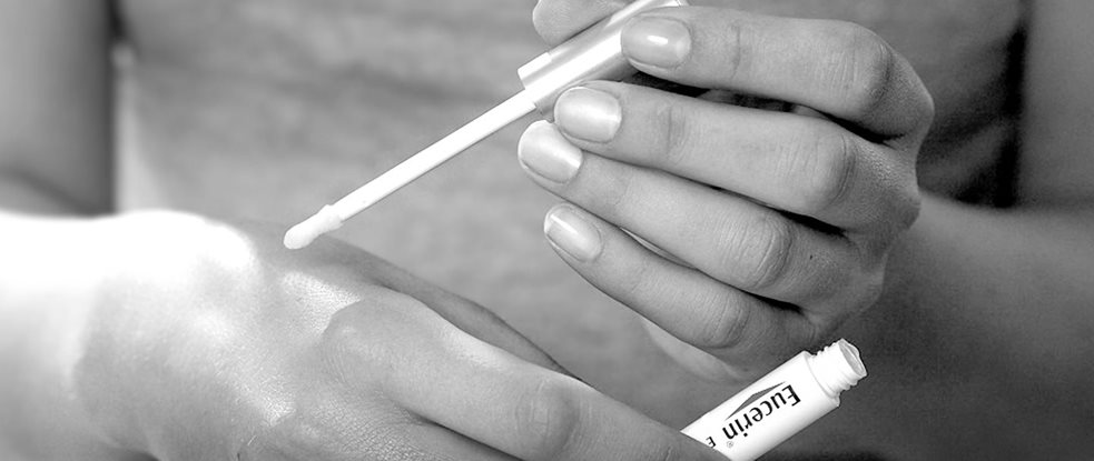 Woman using spot corrector on her left hand