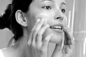 Woman appliying cream on her face"