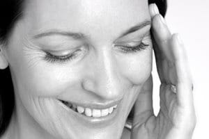 Woman touching her face with her left hand.